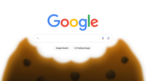 Google search homepage with a large, bitten chocolate chip cookie at the bottom. The search bar and buttons are visible, including one labeled “Google Search” and another labeled “I’m Feeling Hungry.”