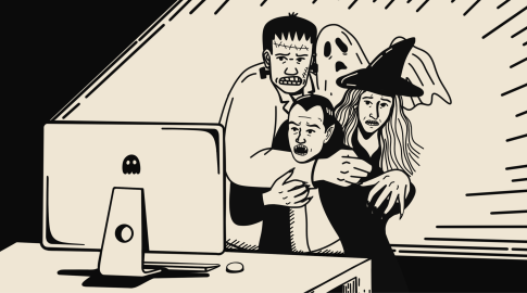 Cartoon illustration of three frightened people dressed as classic horror characters—a Frankenstein monster, a vampire, and a witch with a ghost behind them—huddled together and staring at a computer screen with a ghost icon on it. The background is stylized with lines radiating out, suggesting surprise or fear.
